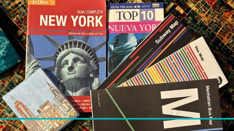 Composición horizontal de dos guías de viaje, mapas de subte y bus de Nueva York junto a un anotador temático de NYC sobre una mesa.