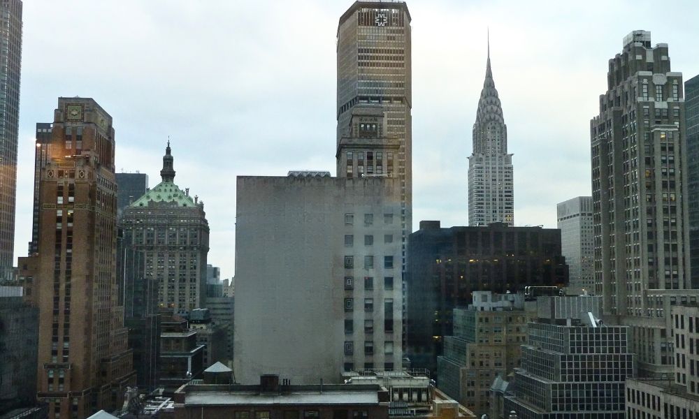 Increíble vista panorámica del edificio Chrysler entre rascacielos de Manhattan desde una ventana del hotel Sofitel New York en un día nublado.