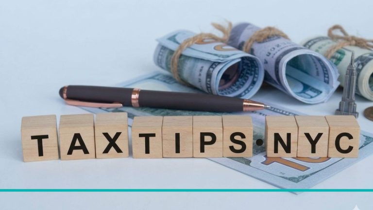 Composición de escritorio con cubos de madera uniformes que forman las palabras TAX TIPS NYC, junto a una lapicera fina, billetes de dólar y una miniatura del Empire State Building.