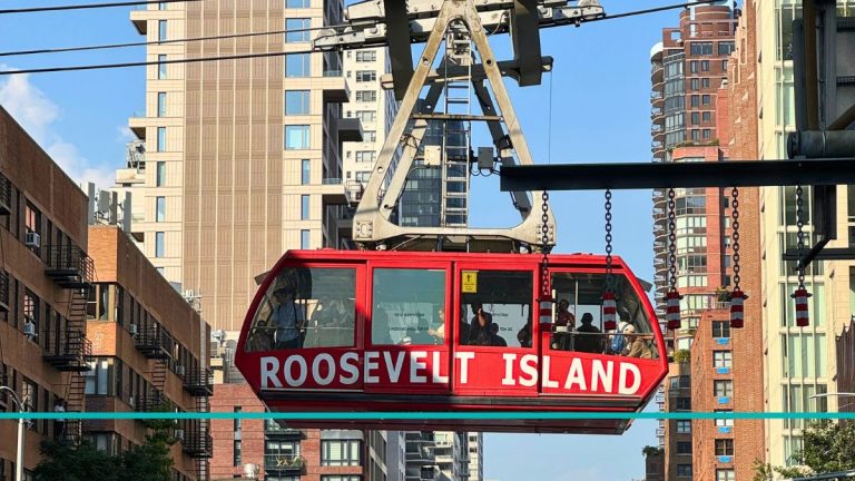 Teleférico rojo de Roosevelt Island pasando por encima de una transitada avenida de Manhattan.