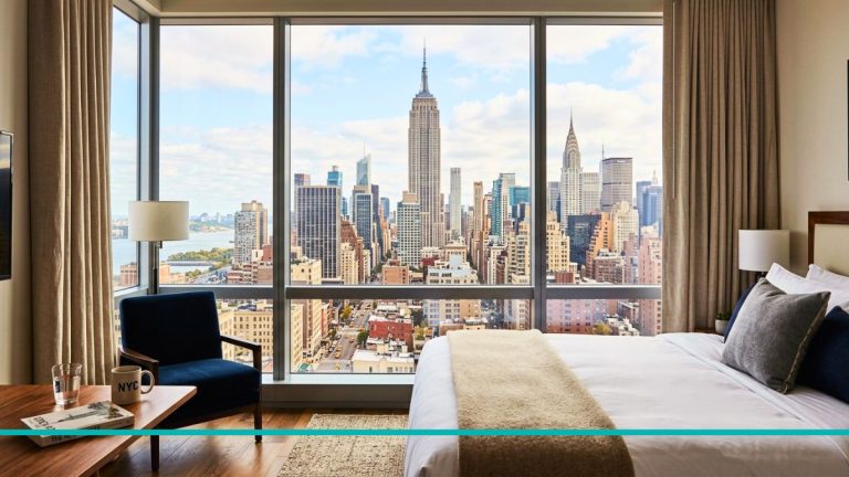 Vista panorámica del skyline de Manhattan con el Empire State Building desde el ventanal de una habitación de hotel de lujo en Nueva York.