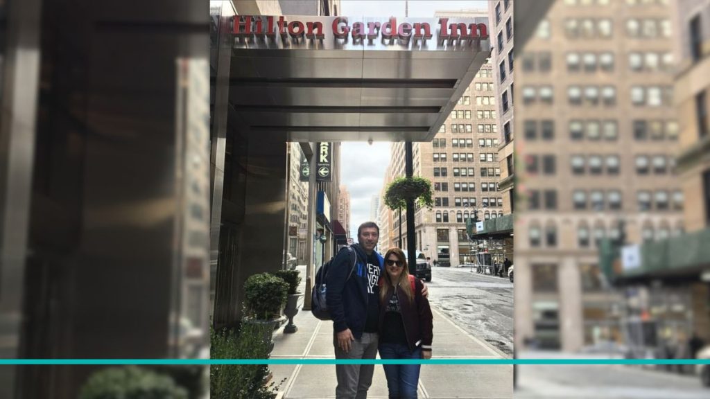 Pareja celebrando un cumpleaños frente al cartel del hotel Hilton Garden Inn Midtown Park Avenue en las calles de Nueva York.