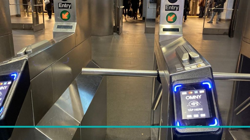 Primer plano de la pantalla digital de un molinete de subte mostrando el lector OMNY para pagos sin contacto en Nueva York.