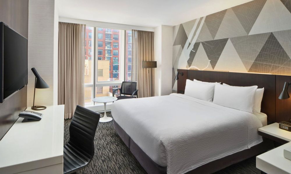 Interior de una habitación moderna y luminosa en el hotel Courtyard by Marriott LIC con cama King y escritorio.